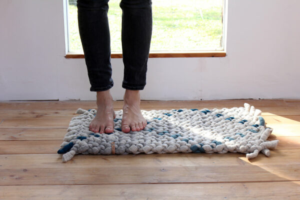 Teppich aus Schafwolle grau, beige türkis auf Holzboden, Füße auf dem Teppich, Merinowolle aus Deutschland