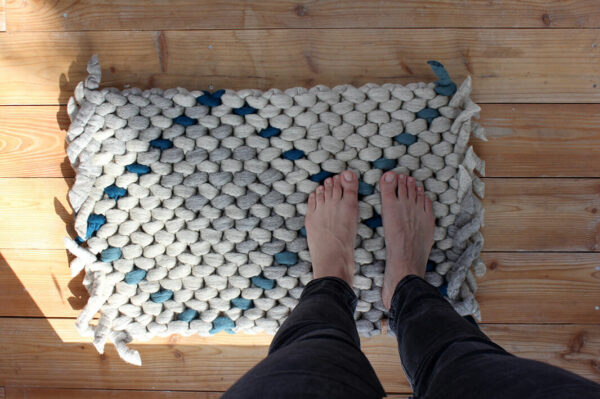 Teppich aus Schafwolle beige grau türkis auf Holzboden, Füße auf dem Teppich, Merinowolle aus Deutschland