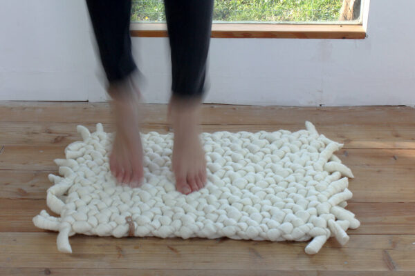 Teppich aus Schafwolle weiß auf Holzboden, Füße auf dem Teppich, Merinowolle aus Deutschland